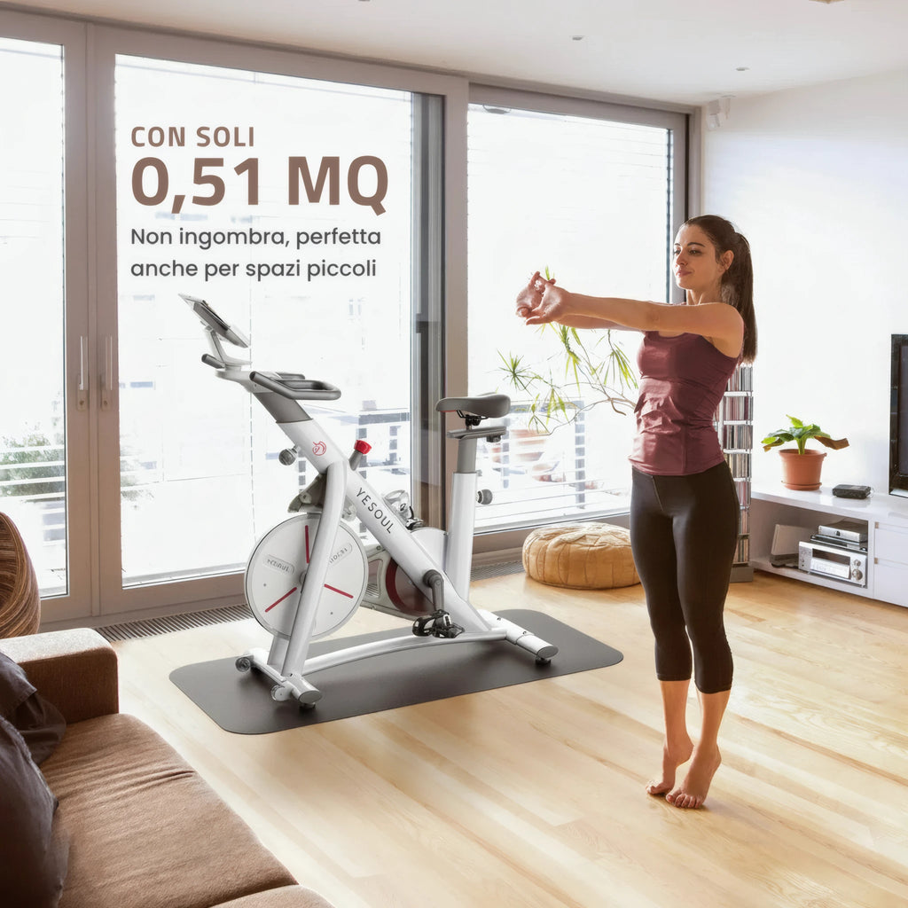 Donna che si allena in casa davanti a una bike indoor Yesoul S3 posizionata in un soggiorno luminoso, con ingombro ridotto adatto anche a spazi piccoli